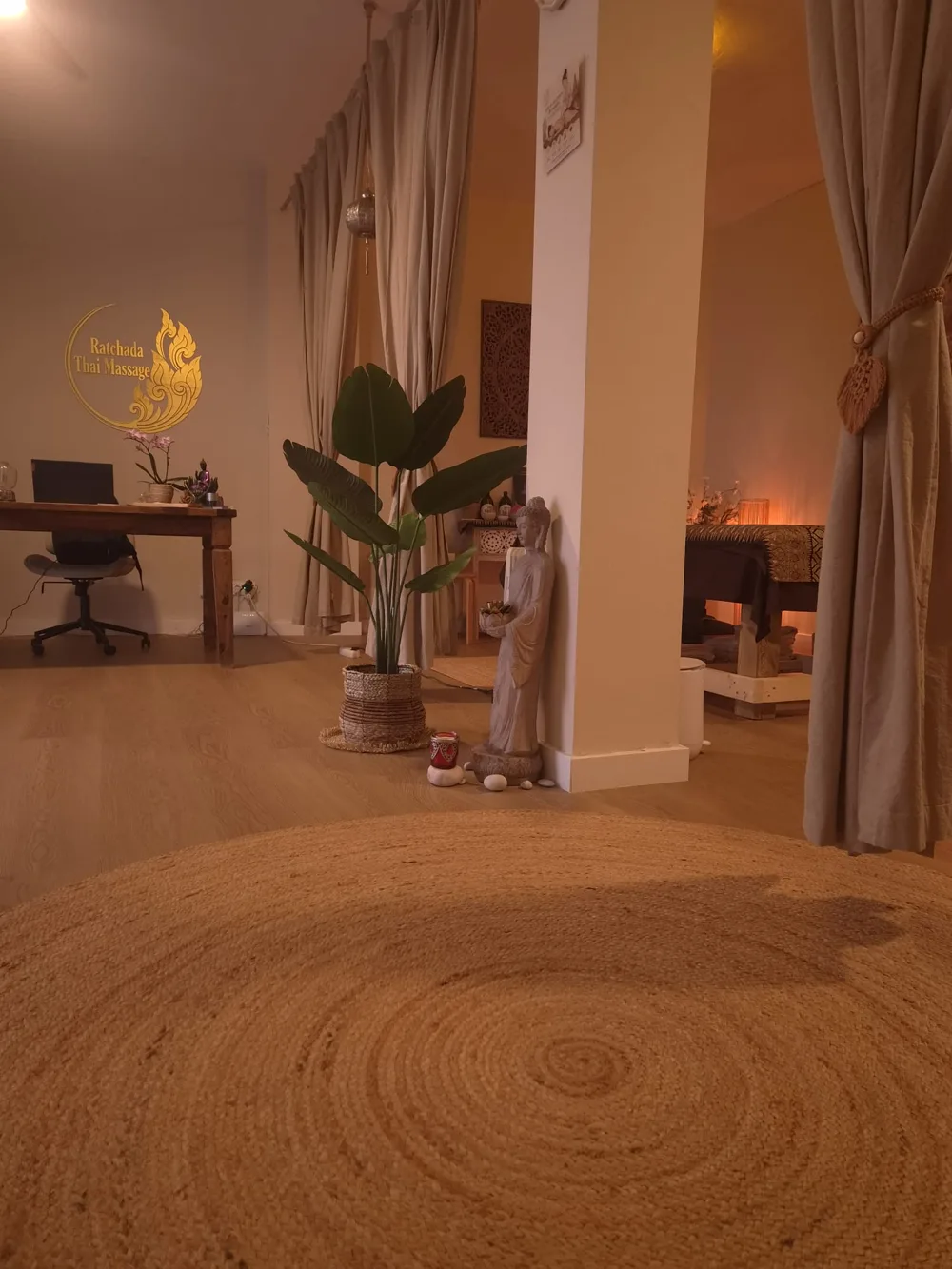 Recepció vista des de la sala, amb catifa de jute, una planta i el Buda dret al costat de la columna